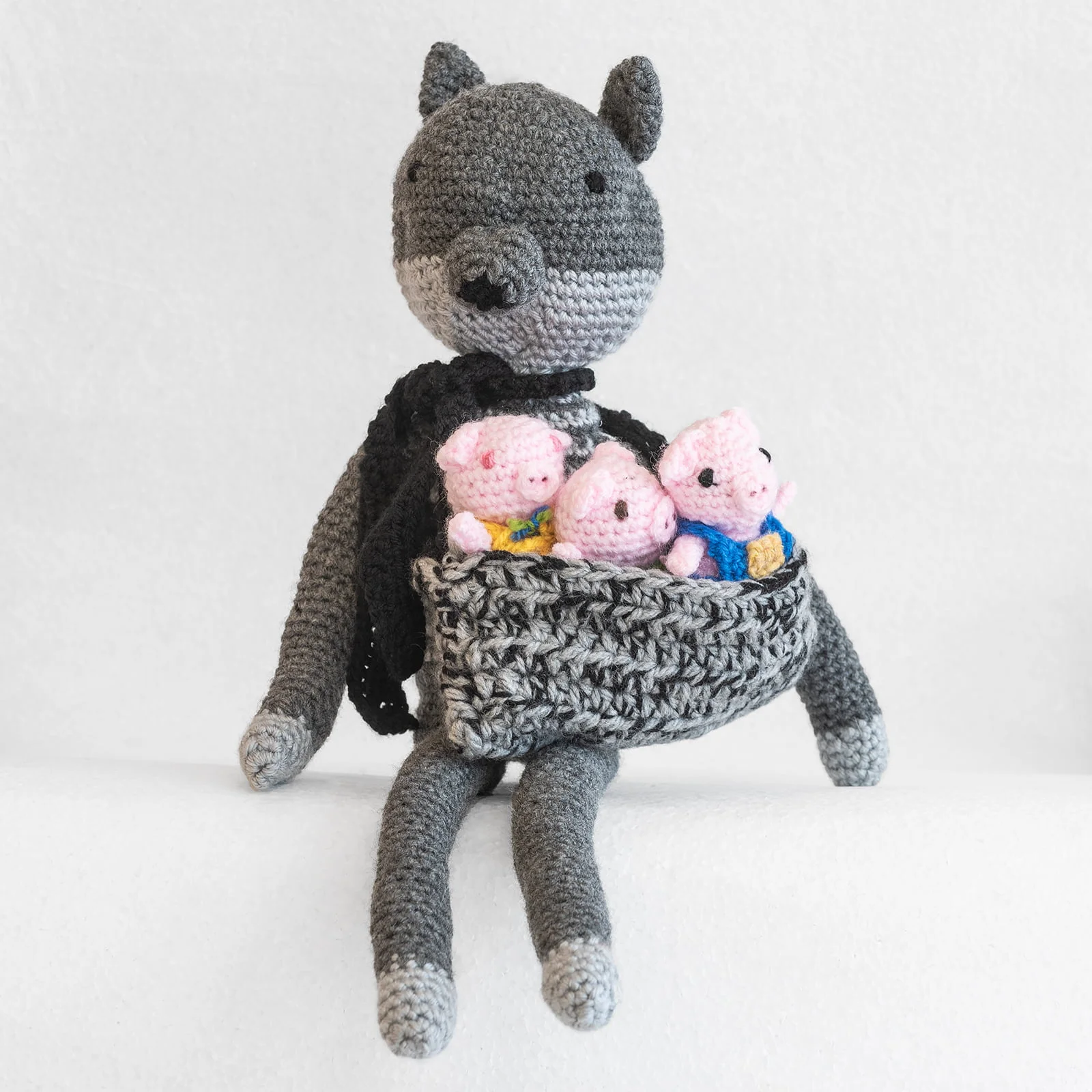 hand knitted pigs in a basket with wolf