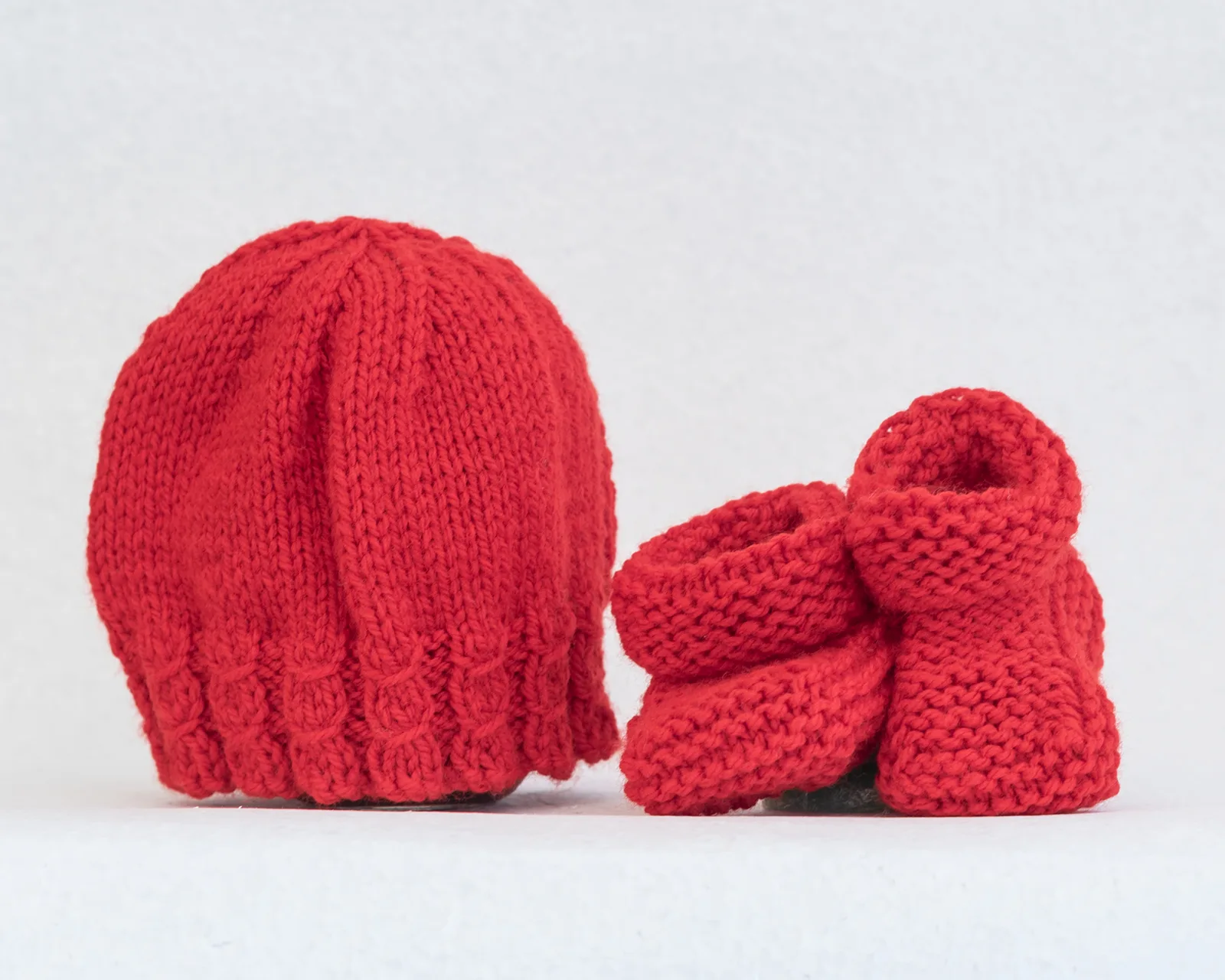 red knitted hat and booties for newborn baby